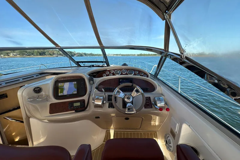 Slide: The Image of 1999 Sea Ray 380 Sundancer helm with navigation equipment, steering wheel, and water view. - 13