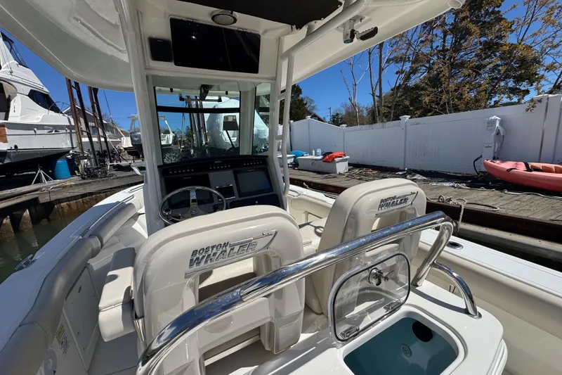 Slide: The Image of 2017 Boston Whaler 250 Outrage boat interior with helm and seating, docked outdoors. - 11