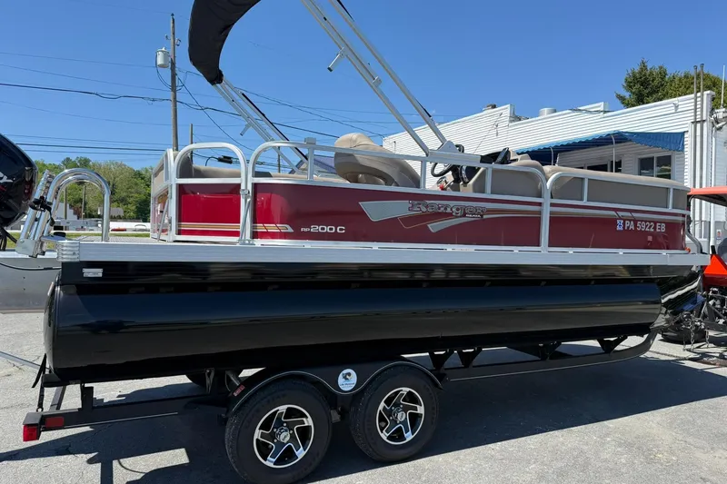 Slide: The Image of 2022 Ranger 200C pontoon boat on trailer, red and black design, parked outdoors. - 5