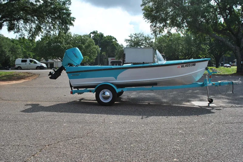 Slide: The Image of 2025 Starcraft 57 Ski Champ boat on trailer in parking lot, surrounded by trees. - 5