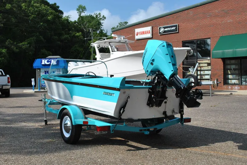 Slide: The Image of 2025 Starcraft 57 Ski Champ boat on trailer, parked outside a marine store. - 7