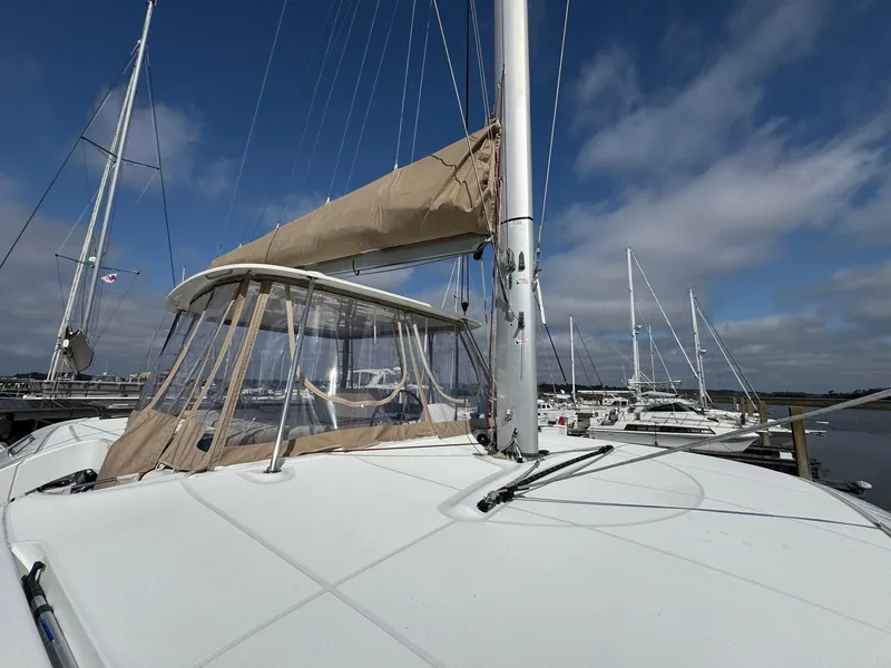 Slide: The Image of 2022 Lagoon 46 catamaran docked, featuring beige sail cover and clear canopy under a blue sky. - 20