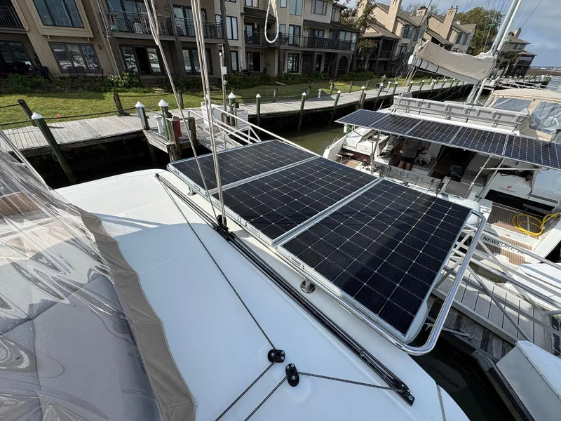 Slide: The Image of 2022 Lagoon 46 catamaran with solar panels docked at a marina. - 23