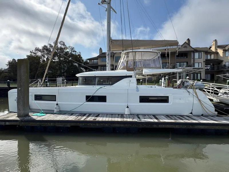 Slide: The Image of 2022 Lagoon 46 catamaran docked at a marina, with residential buildings in the background. - 5