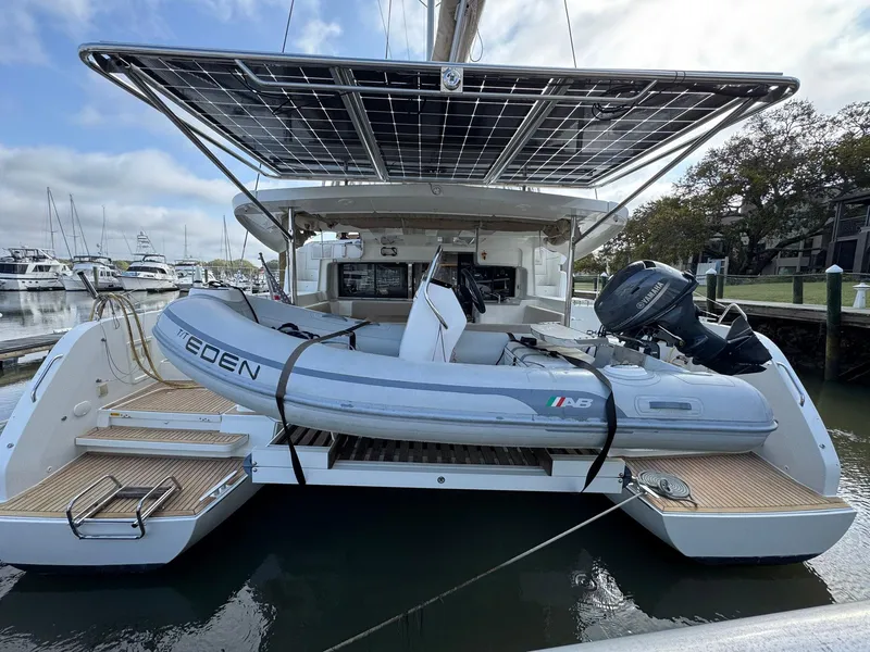 Slide: The Image of 2022 Lagoon 46 catamaran with dinghy, docked at marina, featuring solar panels. - 6