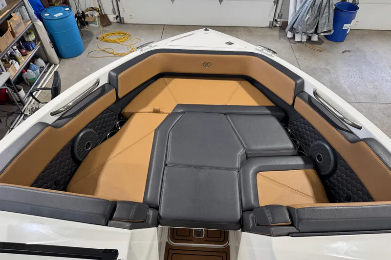Slide: The Image of 2023 Cobalt R6 Surf boat interior with tan and black seating in a garage setting. - 20
