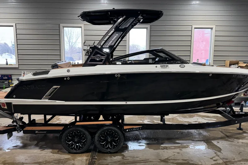 Slide: The Image of 2023 Cobalt R6 Surf boat in a garage, black exterior, on a trailer. - 3
