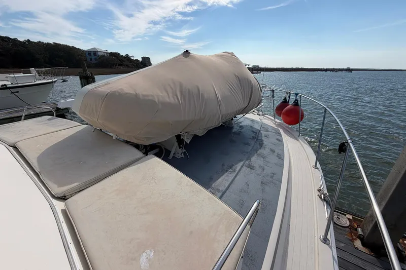 Slide: The Image of 1987 Viking 44 Motor Yacht docked, covered, with scenic water and sky backdrop. - 12
