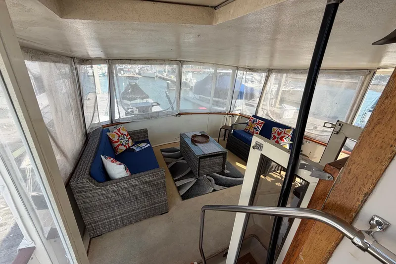 Slide: The Image of 1987 Viking 44 Motor Yacht interior with wicker seating, colorful cushions, and marina view. - 25