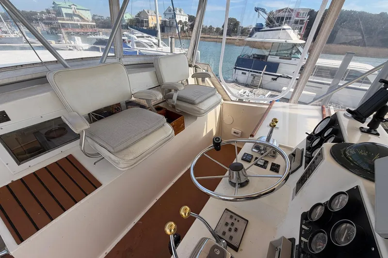Slide: The Image of 1987 Viking 44 Motor Yacht helm with steering wheel, controls, and seating, docked at marina. - 33