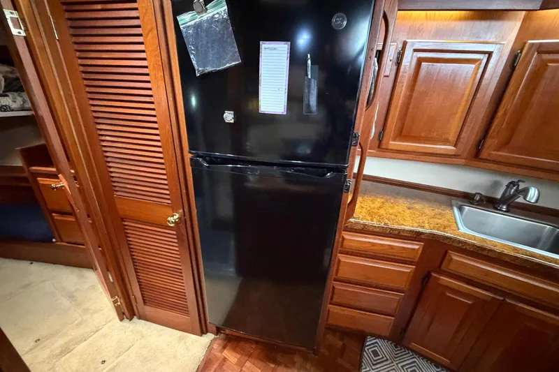 Slide: The Image of 1987 Viking 44 Motor Yacht kitchen with black fridge, wooden cabinets, and sink. - 52