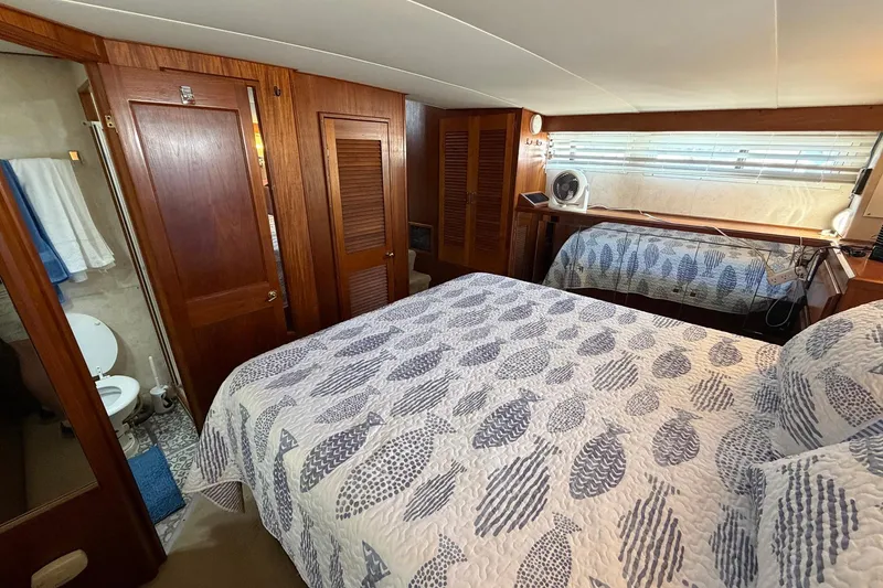 Slide: The Image of 1987 Viking 44 Motor Yacht bedroom with patterned bedding and wooden cabinetry. - 56