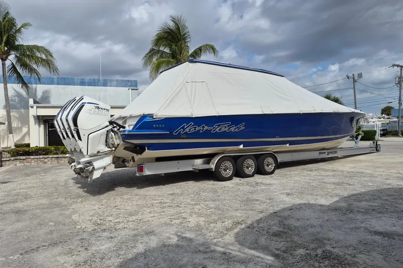 Slide: The Image of 2020 Nor-Tech 450 Sport Center Console boat on trailer, covered, with palm trees in background. - 28