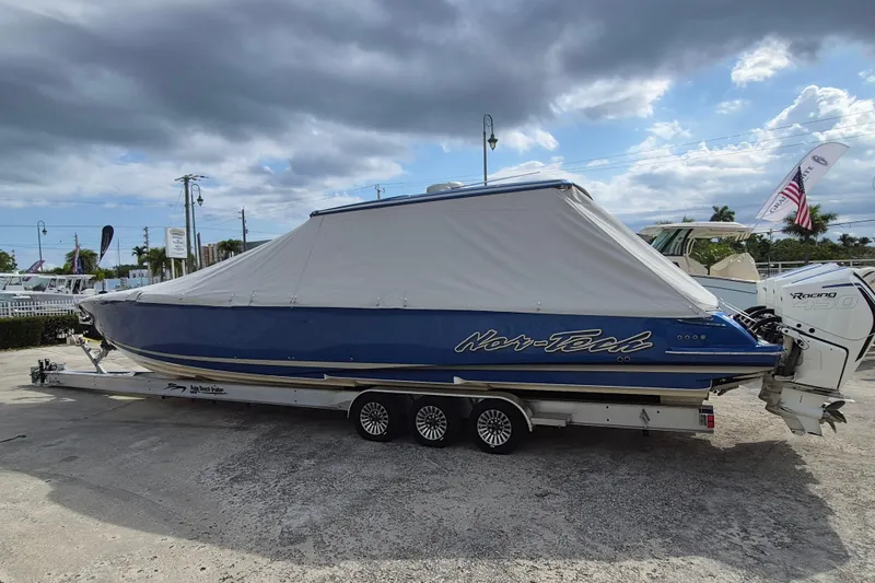 Slide: The Image of 2020 Nor-Tech 450 Sport Center Console boat on trailer, covered, under cloudy sky. - 29