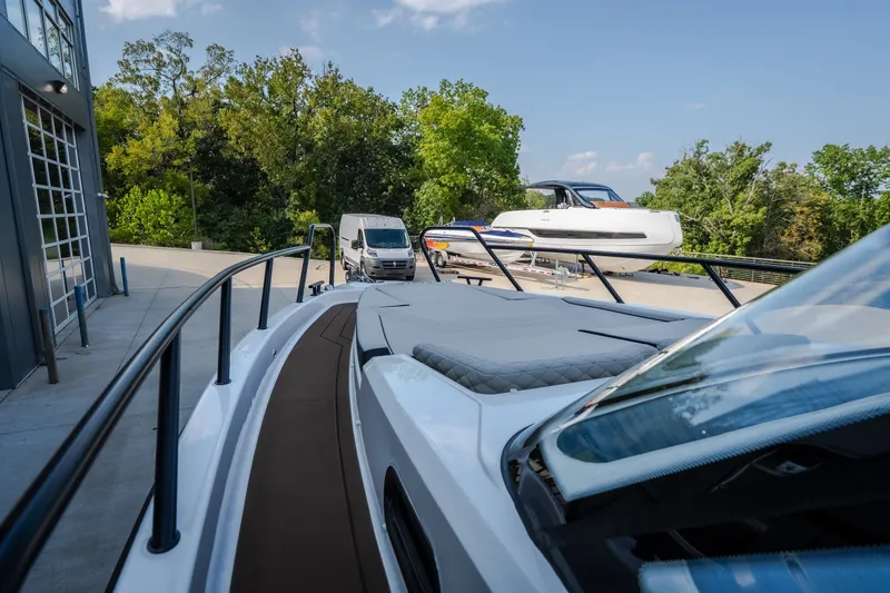 Slide: The Image of 2025 Navan S30 boat docked near a modern building, surrounded by trees and vehicles. - 54