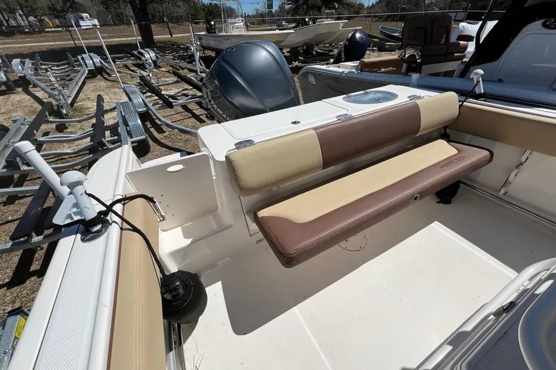 Slide: The Image of 2018 ROBALLO R242 boat interior with beige seating and motor, parked on a trailer. - 12