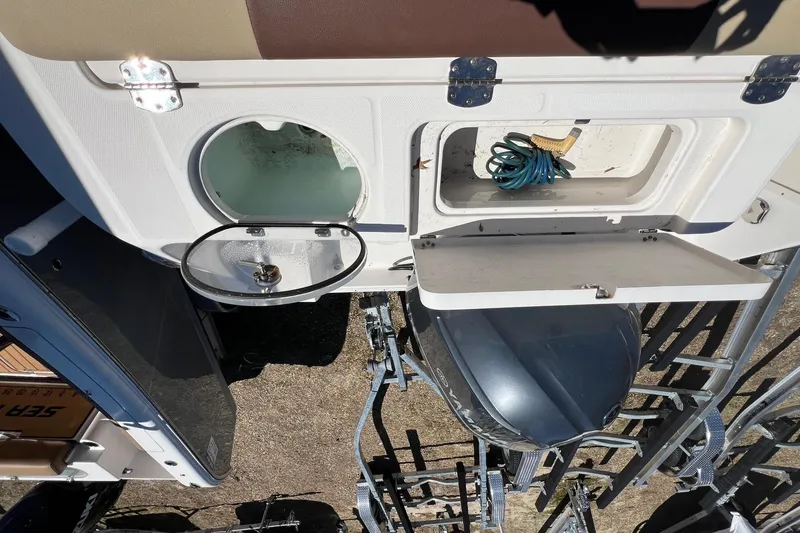 Slide: The Image of 2018 ROBALLO R242 boat storage compartments with coiled hose and open hatch. - 13