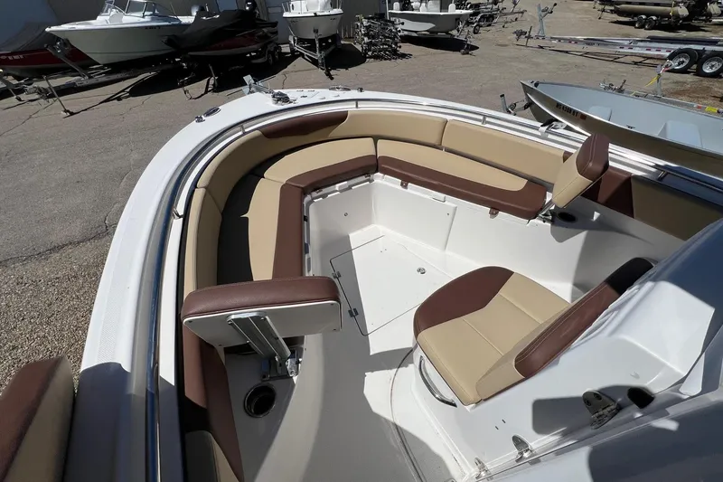 Slide: The Image of 2018 ROBALLO R242 boat interior with tan and brown seating, docked among other boats. - 18