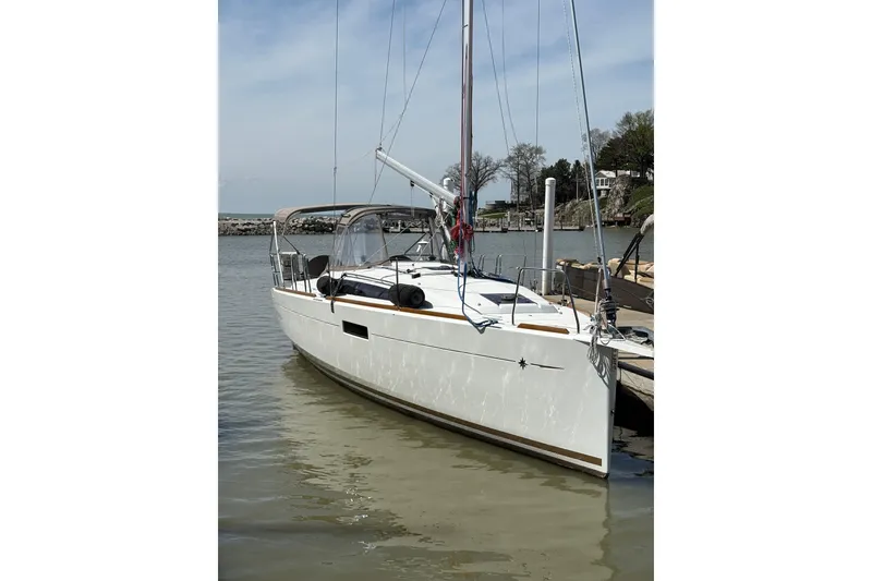 The Image of 2017 Jeanneau Sun Odyssey 349 sailboat docked in a serene marina setting. - 0
