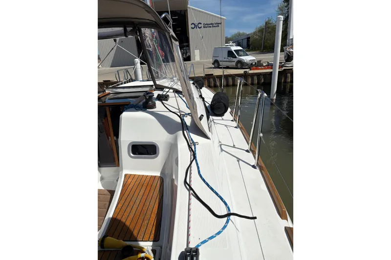Slide: The Image of 2017 Jeanneau Sun Odyssey 349 sailboat docked at a marina, showcasing deck and rigging. - 22