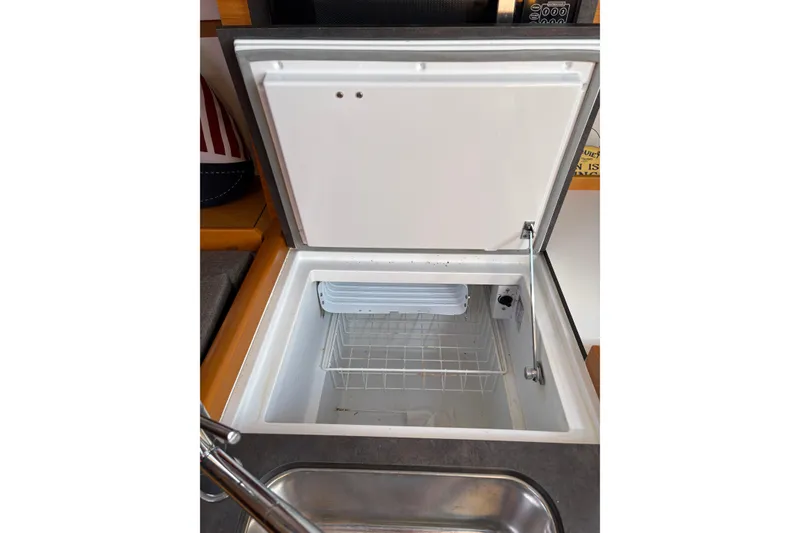Slide: The Image of Open refrigerator in 2017 Jeanneau Sun Odyssey 349 yacht galley, featuring wire basket storage. - 36