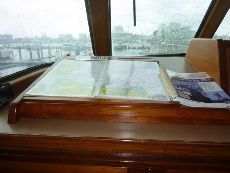 Slide: The Image of Navigation station on 1987 Hatteras Flybridge with maps and guidebook. - 13