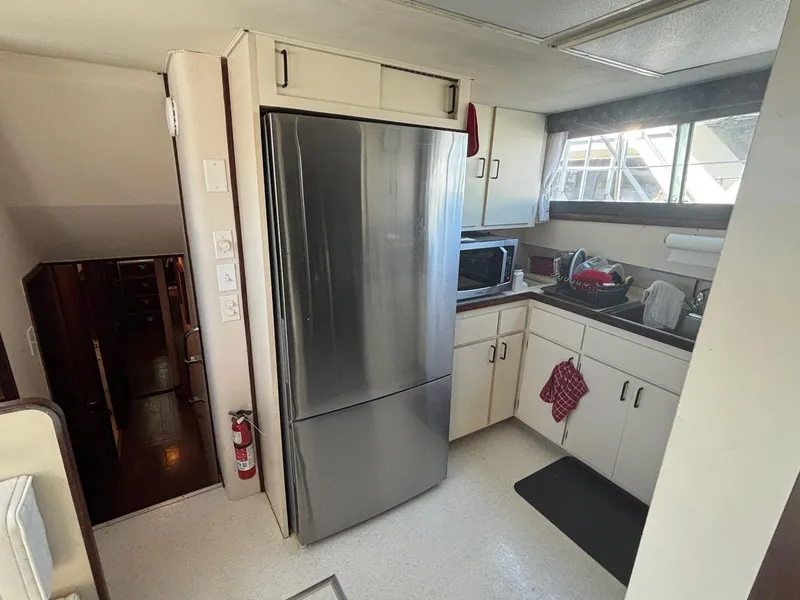 Slide: The Image of 1987 Hatteras Flybridge kitchen with stainless steel fridge, microwave, and sink area. - 14