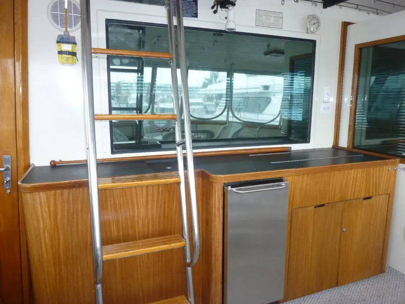 Slide: The Image of 1987 Hatteras Flybridge interior with wooden cabinetry, ladder, and window view. - 30