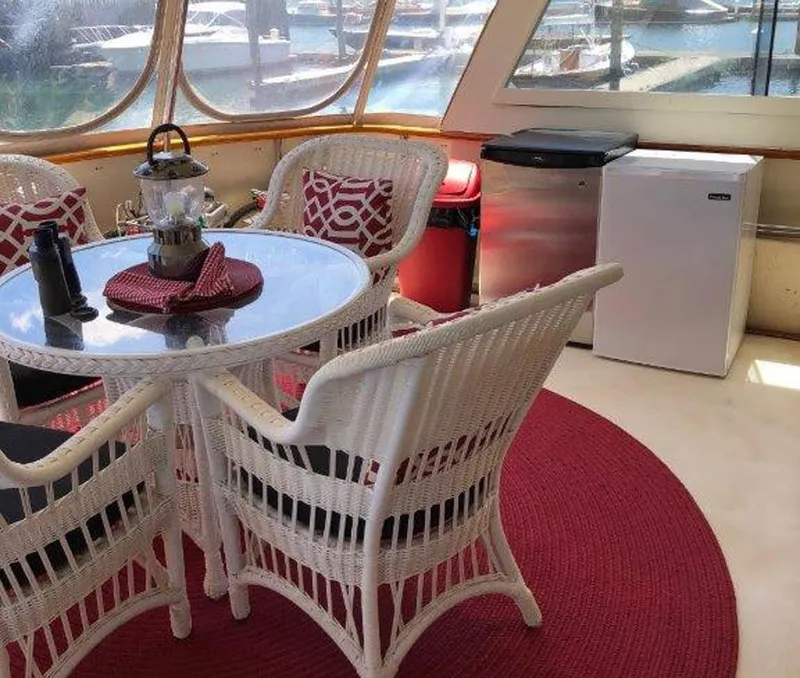 Slide: The Image of 1987 Hatteras Flybridge interior with wicker chairs, round table, and marina view. - 36