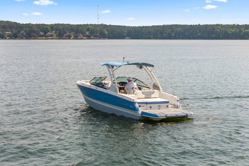 The Image of 2022 Chaparral 247 SSX boat cruising on a serene lake under a clear sky. - 1