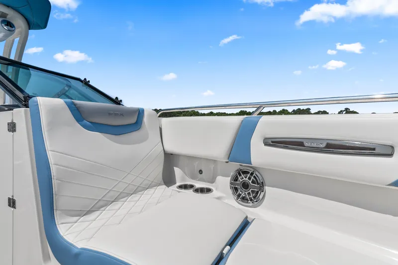 Slide: The Image of 2022 Chaparral 247 SSX boat interior with white and blue seating under a clear sky. - 14