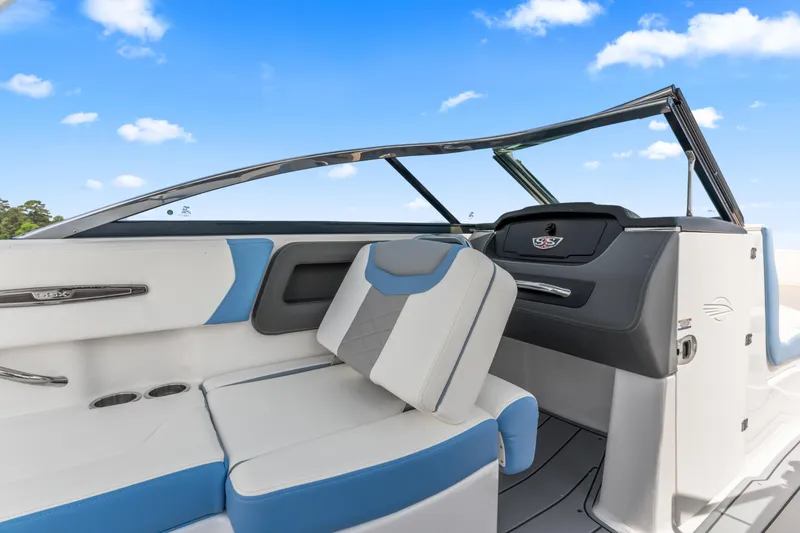 Slide: The Image of 2022 Chaparral 247 SSX boat interior with blue and white seating under a clear sky. - 16
