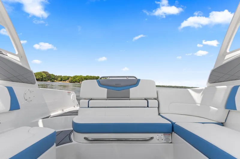 Slide: The Image of 2022 Chaparral 247 SSX boat interior with white and blue seating, under clear sky. - 20