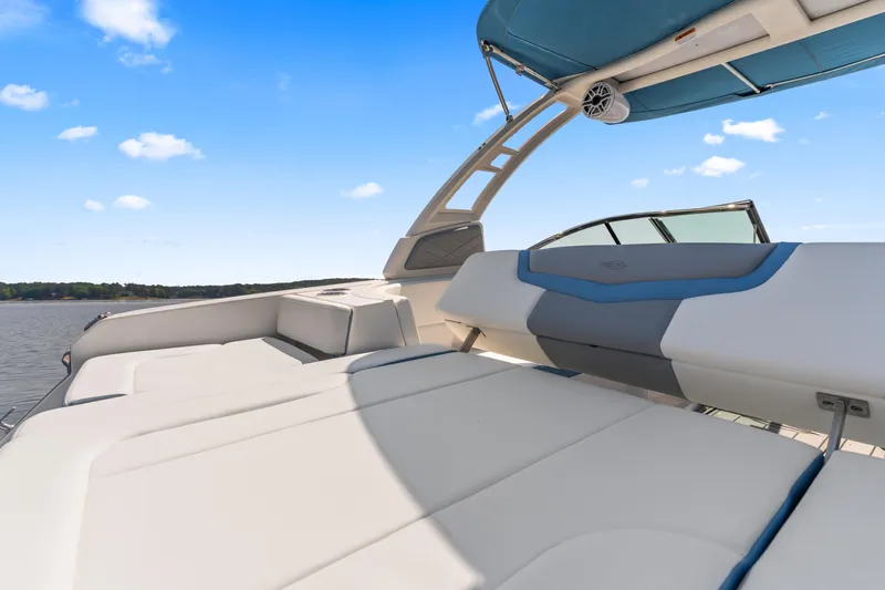 Slide: The Image of 2022 Chaparral 247 SSX boat interior with cushioned seating and blue canopy on a sunny day. - 22