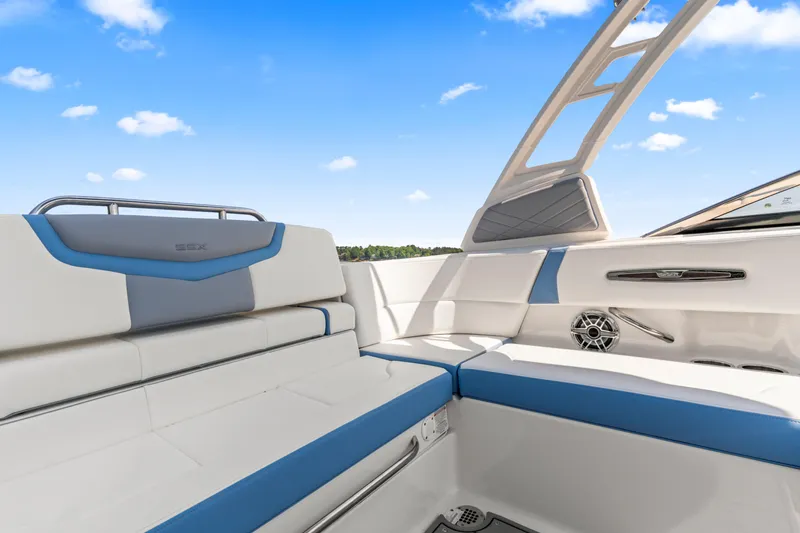 Slide: The Image of 2022 Chaparral 247 SSX boat interior with white and blue seating under a clear sky. - 23