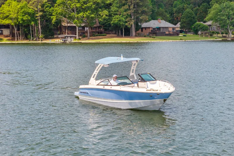 Slide: The Image of 2022 Chaparral 247 SSX boat cruising on a serene lake near wooded shoreline. - 3