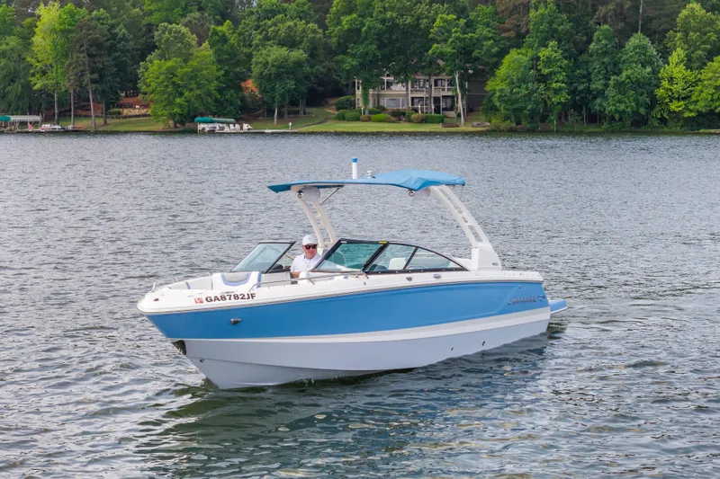 Slide: The Image of 2022 Chaparral 247 SSX boat cruising on a lake with lush green shoreline. - 4