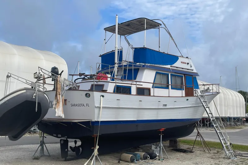 Slide: The Image of 1981 Albin 36 Trawler docked in Sarasota, FL, with blue canopy and ladder access. - 10