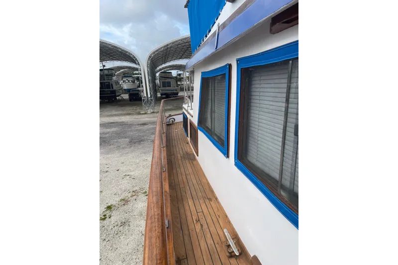 Slide: The Image of 1981 Albin 36 Trawler with wooden deck and blue-trimmed windows in a boatyard. - 11