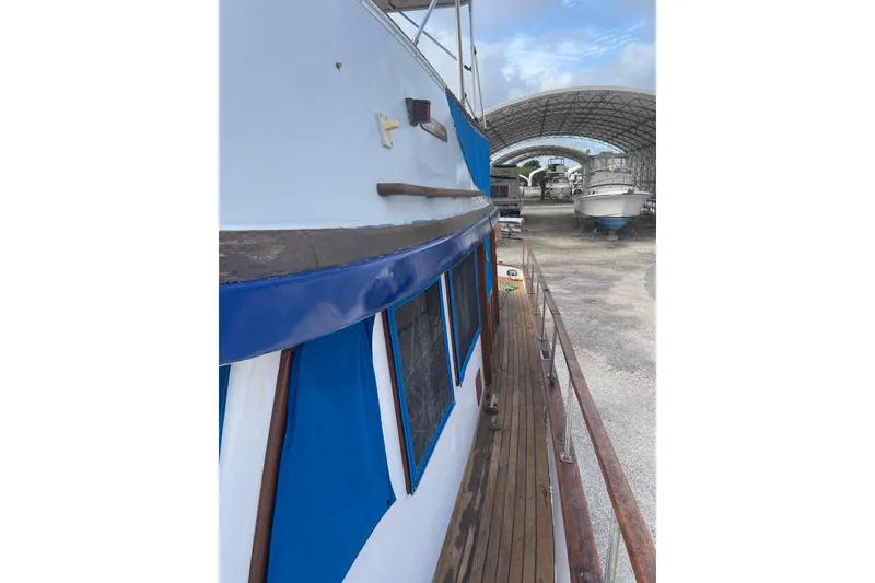 Slide: The Image of 1981 Albin 36 Trawler docked, showcasing wooden deck and blue canopy. - 15