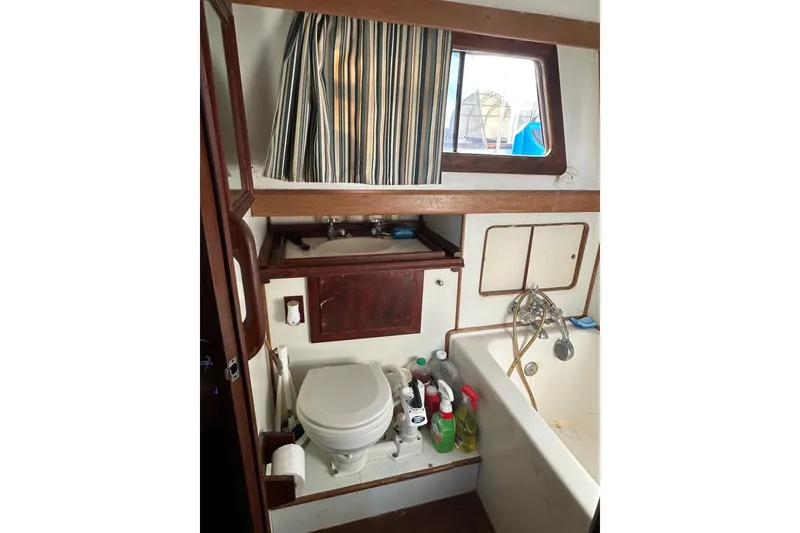 Slide: The Image of 1981 Albin 36 Trawler bathroom with toilet, sink, and cleaning supplies. - 33