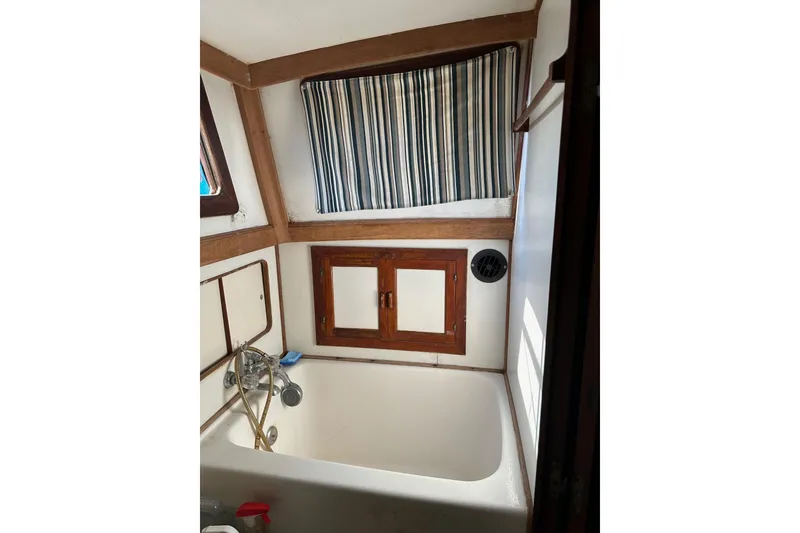 Slide: The Image of Interior of 1981 Albin 36 Trawler bathroom with tub, striped curtain, and wooden accents. - 36