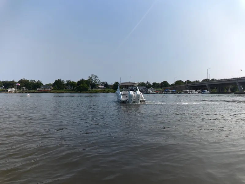 Slide: The Image of A 2027 Sea Ray SLX 310 Outboard cruising on a calm river under a bridge. - 5