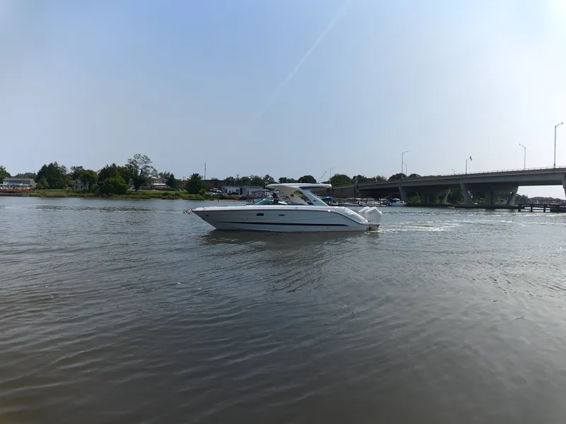Slide: The Image of 2027 Sea Ray SLX 310 Outboard cruising on a calm river near a bridge. - 1