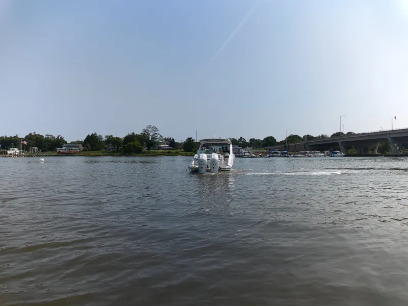 Slide: The Image of A 2027 Sea Ray SLX 310 Outboard cruising on a calm river under a bridge. - 7
