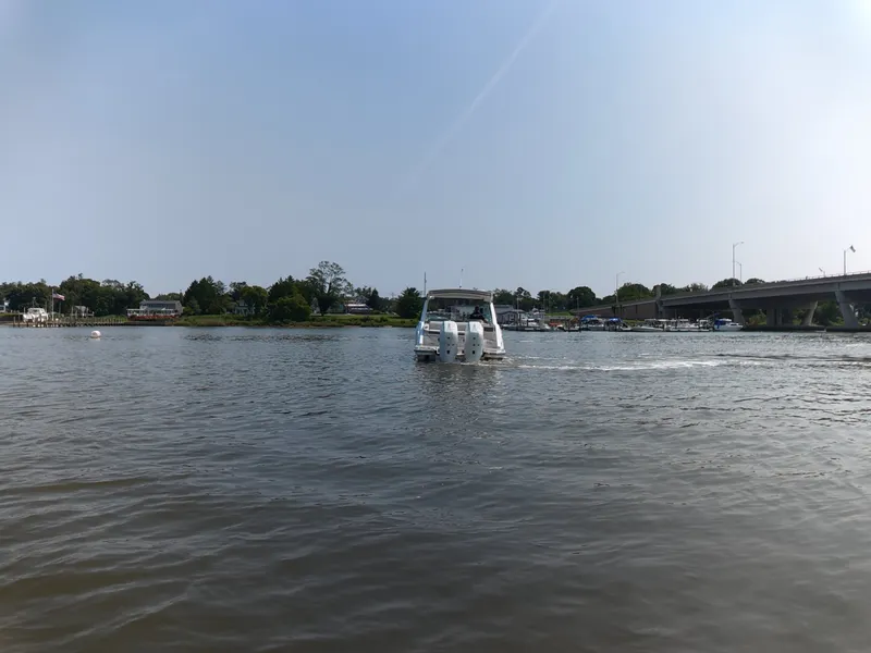 Slide: The Image of A 2027 Sea Ray SLX 310 Outboard cruising on a calm river under a bridge. - 6