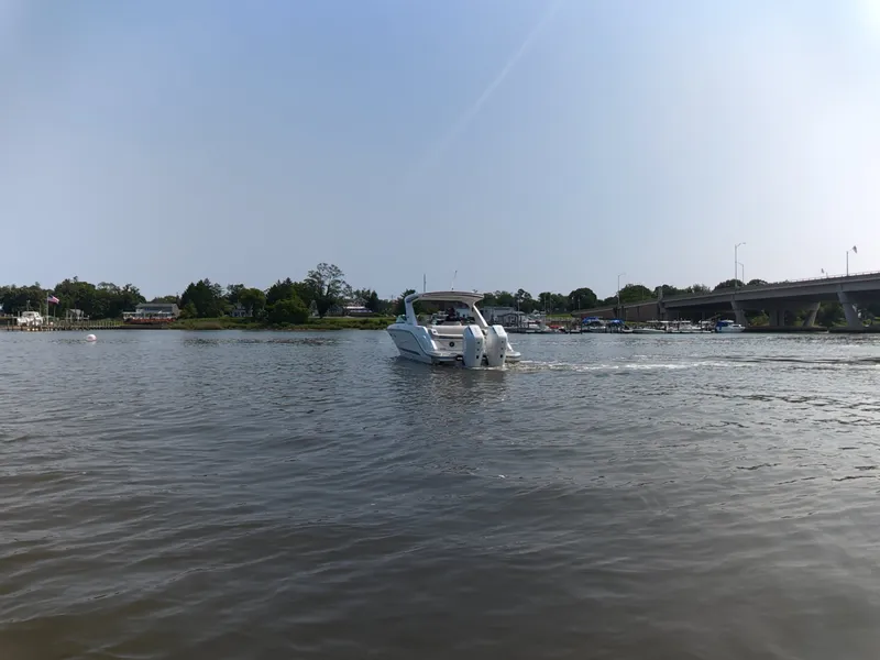 Slide: The Image of Sea Ray SLX 310 Outboard 2027 on calm water with a bridge in the background. - 4