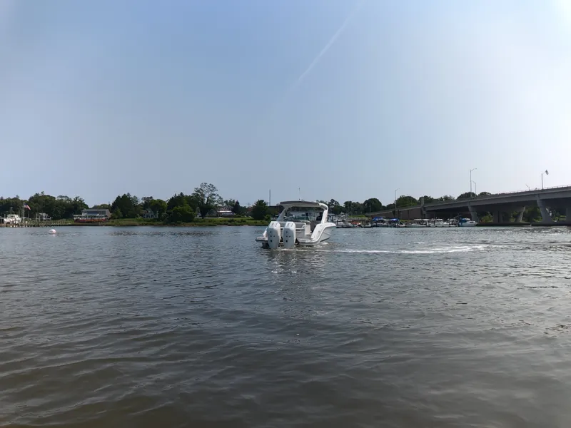 Slide: The Image of Sea Ray SLX 310 Outboard 2027 on calm water near a bridge. - 8