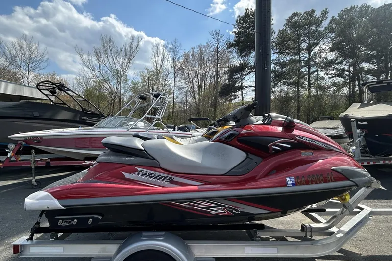 The Image of 2011 Yamaha WaveRunner FZS in red, parked on a trailer, with boats in the background. - 1