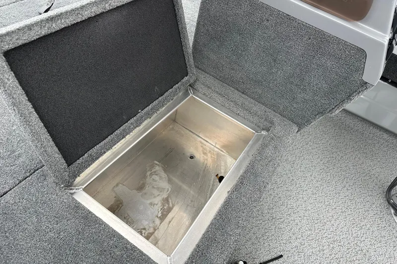 Slide: The Image of Open storage compartment in 2025 Smoker Craft Resorter 151 boat, featuring carpeted interior. - 10
